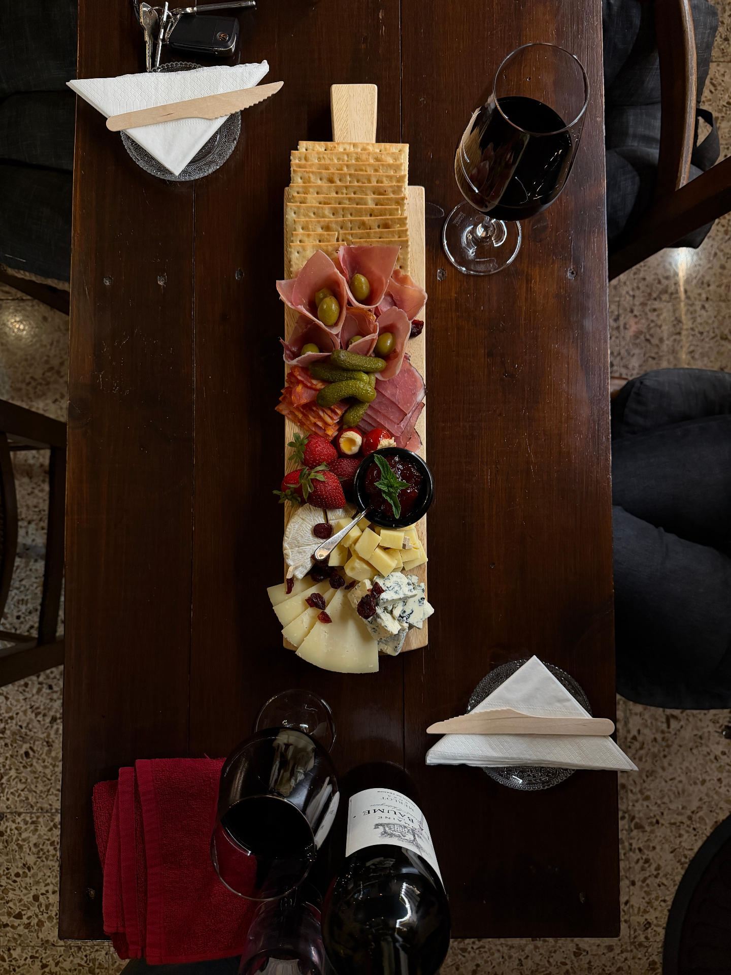 Overhead shot of long charcuterie board with red wine